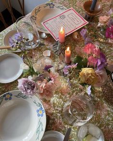 a table topped with plates and flowers next to a lit candle