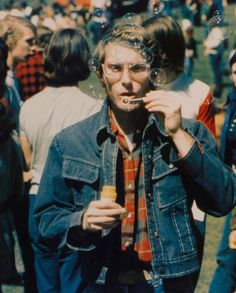 a man blowing bubbles on his face while standing in front of a group of people