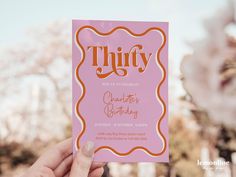 a person holding up a pink and orange birthday card