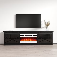 an entertainment center with a television mounted on the wall and fire burning in the fireplace