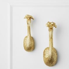 two golden bird shaped hooks on a white wall