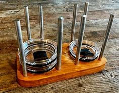 a set of four glass jars with metal lids on a wooden stand, sitting on a wood surface