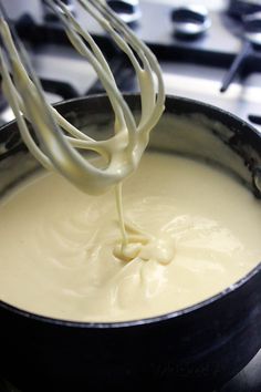 a whisk is being used to mix cream in a pan