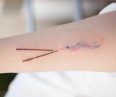 a woman's arm with two wands and stars painted on the back of it