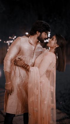 a man and woman standing next to each other with sparklers in the air behind them