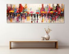 an abstract painting of people with umbrellas on a white wall above a coffee table