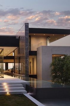 a modern house with steps leading up to the front door and patio area at dusk