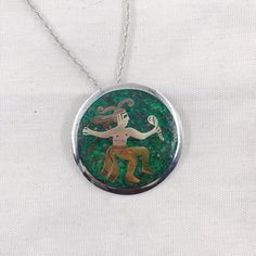 This vintage Mexican Silver piece functions as both a pendant and a brooch.  The piece features a green background with married metal overlay to create a figure in traditional dress.  This pendant comes with a 24" sterling silver wheat chain and is in good vintage condition.Stamps: Metales casadas (married metals) Mexico 925 Sterling Taxco Diameter: 68 mm/2 1/8 inchChain: 24 inch wheat styleThese pieces are pre-owned vintage jewelry. As this jewelry is not new there may be signs of wear or age. Green Sterling Silver Brooch Jewelry, Green Sterling Silver Brooch, Sterling Silver Green Brooch, Green Sterling Silver Medallion Jewelry, Green Medallion Sterling Silver Jewelry, Green Engraved Necklace For Collectors, Green Medallion Jewelry With Large Pendant, Green Medallion Pendant Jewelry, Traditional Green Brooch Jewelry