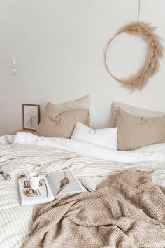 a bed with white sheets, pillows and a wreath hanging on the wall above it