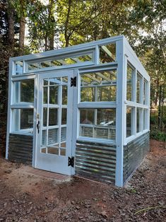 a small blue building sitting in the middle of a forest