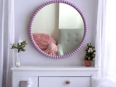 a white dresser topped with a pink mirror