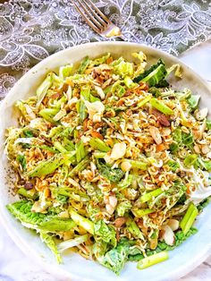 a white bowl filled with broccoli and nuts on top of a lace table cloth