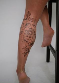 a woman's leg with flowers on it, sitting in front of a stool