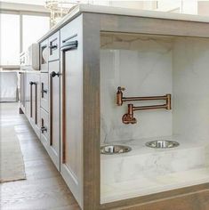 a kitchen with marble counter tops and copper faucets on the sink, in an open cabinet