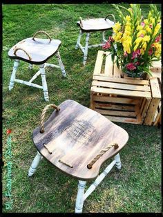 three wooden chairs sitting on top of a grass covered field next to flower vases