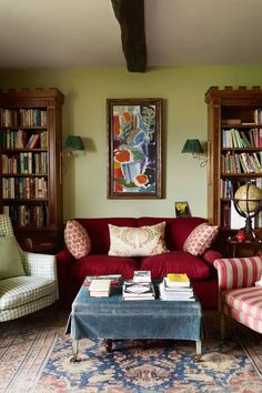 a living room filled with furniture and bookshelves next to a painting on the wall