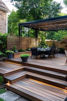 a patio with wooden steps leading up to a dining table and seating area on top of it