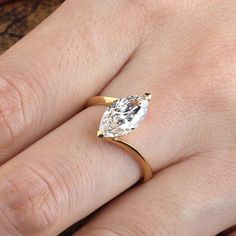 a close up of a person's hand with a diamond ring on their finger