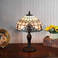 a lamp sitting on top of a wooden table next to a vase with yellow flowers