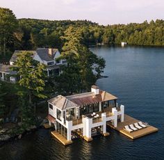 an aerial view of a house on the water with lounge chairs and trees around it