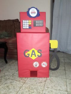 a red gas pump sitting on top of a floor next to a cardboard box that says gas