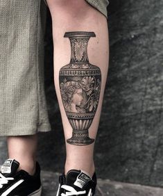 a woman's leg with a vase tattoo on it