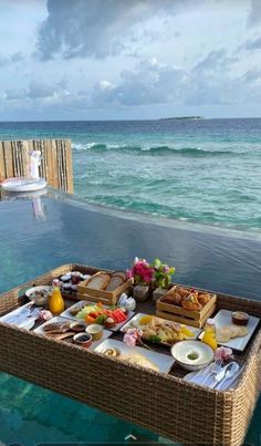 an outdoor table with food on it near the ocean