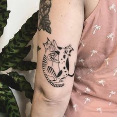 a woman's arm with a cat and dog tattoo on the left side of her arm