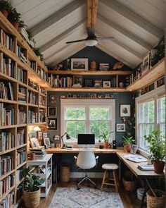 a home office with lots of bookshelves and plants on the desk in front of it