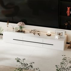 a living room with white furniture and flowers in vases on the floor next to a flat screen tv