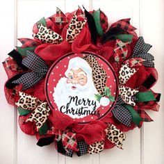 a christmas wreath with a santa clause on it and leopard print ribbon hanging from the front door