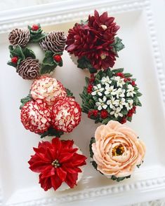 four different types of flowers on a white platter with pine cones and candy canes