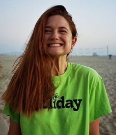 a woman with long red hair standing on the beach