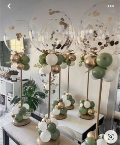 some balloons that are sitting on top of a table with gold and green decorations around them