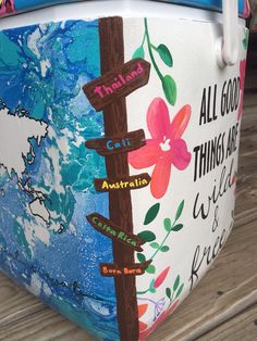 a painted cooler sitting on top of a wooden floor next to a sign that says all good things are possible