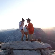 two people standing on top of a mountain next to each other