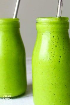 two green smoothies in mason jars with straws sticking out of the top one