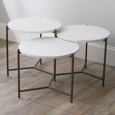 two white marble tables sitting on top of a hard wood floor