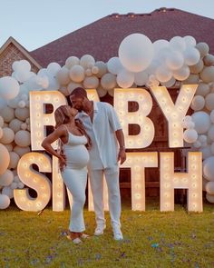 a man and woman standing next to each other in front of a sign that says baby smith