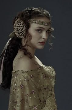 a woman with long hair wearing a dress and head piece in the shape of a fan