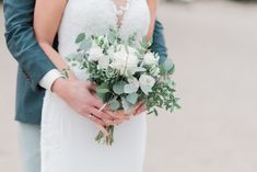 the bride and groom are holding their bouquets in their hands while they stand close to each other