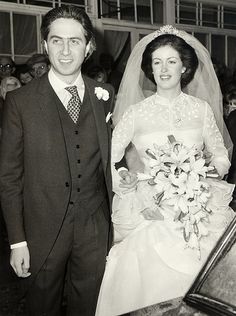 a man and woman are standing next to each other in front of a wedding cake