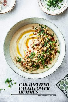 a bowl filled with hummus and garnished with herbs