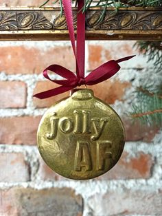 a christmas ornament hanging on a brick wall with a red ribbon around it