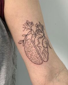 a person with a tattoo on their arm holding a flower and heart shaped object in it