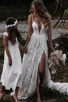 two women in white dresses holding hands while standing next to each other on the grass