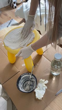 a person in white gloves is kneading something on a table with a bowl