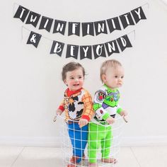 two toddlers standing next to each other in front of a sign that says twenty and beyond