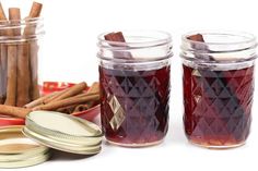 three jars filled with liquid next to cinnamon sticks