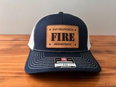 This personalized leather hat features a custom fire department patch. The Richardson 112 hat with the custom leather patch is a stylish and comfortable accessory to wear on your days off or after work. Surprise the firefighter in your life, whether it's a family member, friend, or coworker, with this unique and thoughtful gift that pays tribute to their heroic profession. PRODUCT FEATURES: Patch: Genuine Leather Patch Engraving: Black Brand: Richardson 112 - Adjustable Snapback Trucker Cap Style: Structured, Six-Panel, Mid-Profile Cap Cap Material: 60% Cotton, 40% Polyester Mesh Back Material: 100% Polyester Size: One Size Fits Most, Adjustable Plastic Snapback HOW TO ORDER: Hat Color: Select from the Drop-Down menu Patch Color: Select from the Drop-Down menu Add in the Personalization Ar Firefighter Hat, Leather Patch Trucker Hat 5-panel, Outdoor 5-panel Baseball Cap With Leather Patch, 5-panel Camping Hat With Logo Patch, 5-panel Trucker Hat With Logo Patch For Camping, Leather Patch Hat, Military Hat With Adjustable Logo Patch, Leather Hat, Patch Hat